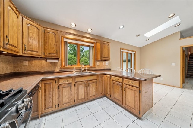 490 Hillside Ave, Monroeville, PA 15146 - kitchen with a sink, vaulted ceiling, a peninsula, backsplash, and stainless steel range with gas cooktop