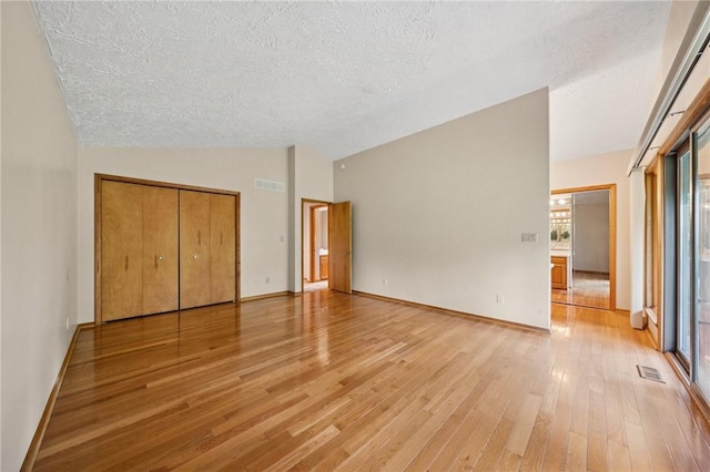490 Hillside Ave, Monroeville, PA 15146 - unfurnished bedroom with vaulted ceiling, a textured ceiling, light wood-style floors, multiple windows, and baseboards