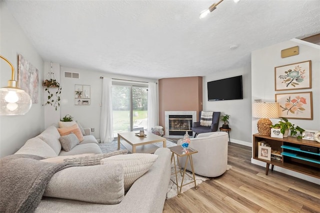 113 Stoney Creek Ct, Seven Fields Boro, PA 16046 - living room featuring a glass covered fireplace, wood finished floors, a textured ceiling, and baseboards