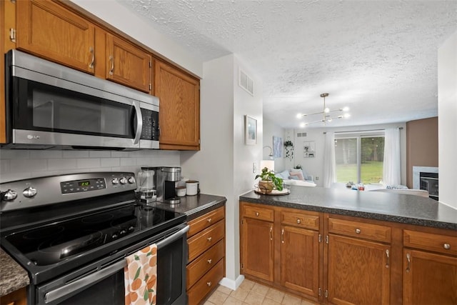 113 Stoney Creek Ct, Seven Fields Boro, PA 16046 - kitchen featuring stainless steel appliances, brown cabinetry, dark countertops, a peninsula, and light tile patterned floors