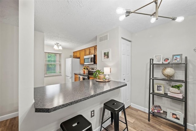 113 Stoney Creek Ct, Seven Fields Boro, PA 16046 - kitchen with appliances with stainless steel finishes, dark countertops, a peninsula, brown cabinets, and a textured ceiling