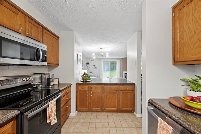 113 Stoney Creek Ct, Seven Fields Boro, PA 16046 - kitchen with stainless steel appliances, brown cabinetry, dark countertops, a textured ceiling, and light tile patterned flooring