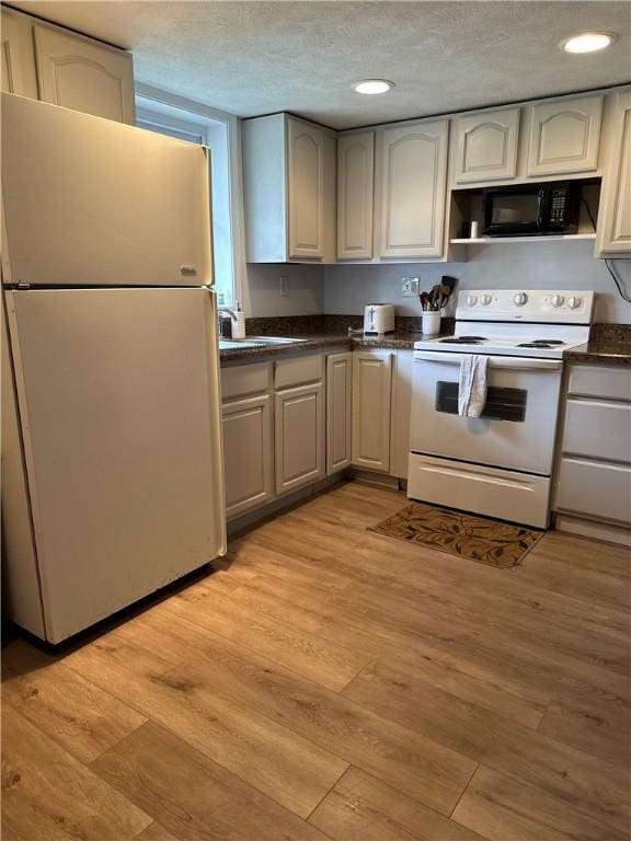 2057 Mccann Dr, Shenango, PA 16424 - kitchen featuring white appliances, dark countertops, light wood-style flooring, recessed lighting, and a sink