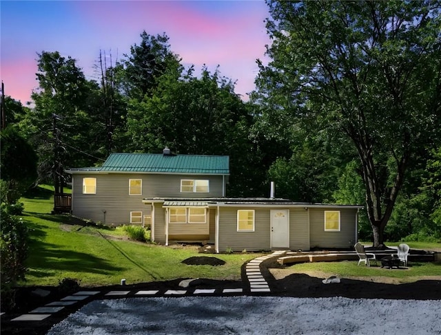 470 Burrell Hill Cir, Penn Twp Wml, PA 15675 - back of house at dusk featuring an outdoor fire pit, a lawn, metal roof, and a standing seam roof