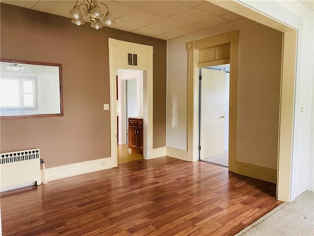 192 W Lincoln St, Waynsbrg/Frankln Twp, PA 15370 - empty room with radiator, a chandelier, a drop ceiling, baseboards, and wood finished floors