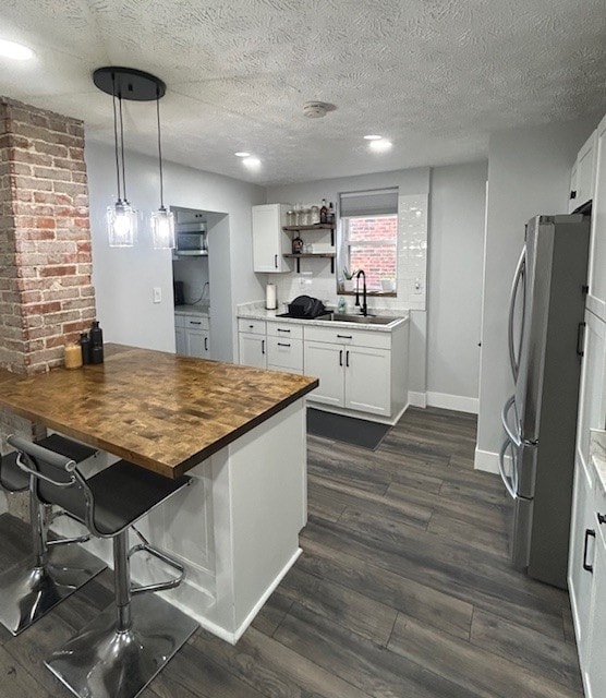 42 Queenston St, Overbrook, PA 15210 - kitchen with wood counters, freestanding refrigerator, a sink, dark wood finished floors, and white cabinetry