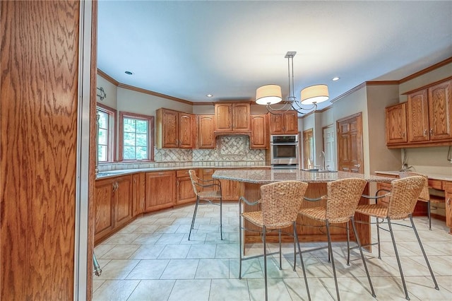 23 Pintail Dr, Indiana Twp Nal, PA 15238 - kitchen with crown molding, a sink, brown cabinetry, backsplash, and a kitchen island with sink