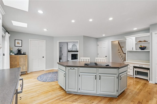 2455 Wedgewood Dr, Franklin Park, PA 15090 - kitchen with black electric stovetop, a center island, dark countertops, a skylight, and light wood-type flooring