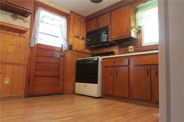 12840 Lincoln Way N, Huntingdon, PA 15642 - kitchen featuring white stove, black microwave, brown cabinetry, light wood-style flooring, and wooden walls