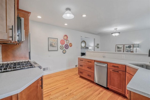 501 Parkview Dr, Mt Lebanon, PA 15243 - kitchen with stainless steel dishwasher, a sink, light countertops, light wood-style flooring, and brown cabinets