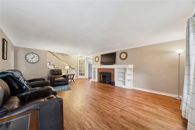 2510 7th St, New Kensington, PA 15068 - living area with wood finished floors, baseboards, a brick fireplace, and stairs