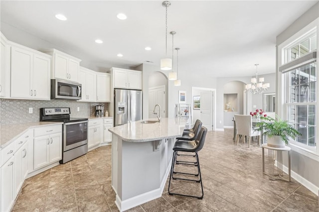 219 Brookside Dr, Cranberry Twp, PA 16066 - kitchen with appliances with stainless steel finishes, backsplash, arched walkways, a sink, and white cabinetry