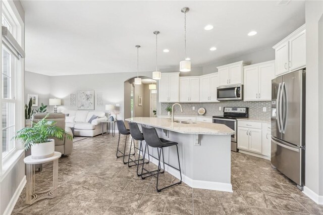 219 Brookside Dr, Cranberry Twp, PA 16066 - kitchen featuring appliances with stainless steel finishes, arched walkways, open floor plan, a sink, and decorative backsplash