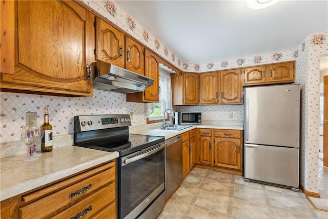 207 Mccartney Dr, Moon/Crescent Twp, PA 15108 - kitchen featuring appliances with stainless steel finishes, under cabinet range hood, brown cabinetry, a sink, and light countertops