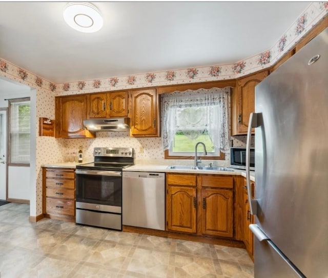 207 Mccartney Dr, Moon/Crescent Twp, PA 15108 - kitchen with appliances with stainless steel finishes, a sink, under cabinet range hood, brown cabinets, and light countertops
