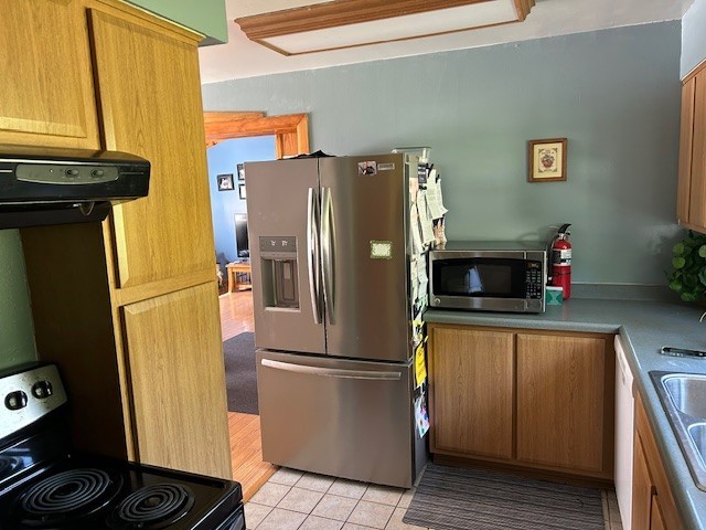 290 Gray Station Rd, Derry Twp, PA 15717 - kitchen with stainless steel appliances, light tile patterned flooring, brown cabinets, and range hood