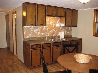 1230 Frank Ave, Jeannette, PA 15644 - kitchen with a sink, wood finished floors, crown molding, and dark brown cabinets