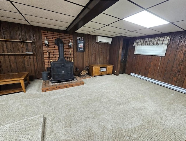 261 Lacock St, Canton Twp, PA 15301 - unfurnished living room featuring a drop ceiling, a wall mounted air conditioner, carpet flooring, a wood stove, and wooden walls