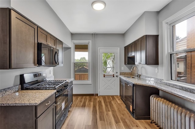 901 Punta Gorda Ave, East Mckeesport, PA 15035 - kitchen featuring radiator heating unit, black appliances, a sink, dark brown cabinetry, and light stone counters