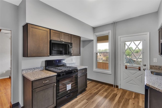 901 Punta Gorda Ave, East Mckeesport, PA 15035 - kitchen featuring black appliances, light wood finished floors, light stone countertops, baseboards, and dark brown cabinets