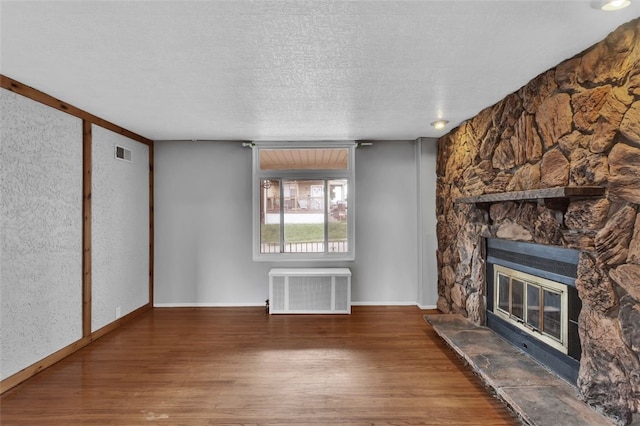 901 Punta Gorda Ave, East Mckeesport, PA 15035 - unfurnished living room featuring radiator heating unit, wood finished floors, a fireplace, a textured ceiling, and baseboards