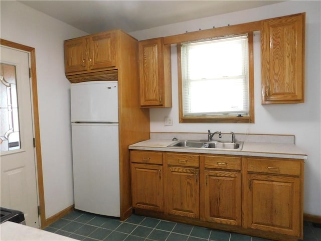 2300 Fairland St, Overbrook, PA 15210 - kitchen with freestanding refrigerator, a sink, light countertops, brown cabinets, and dark tile patterned floors