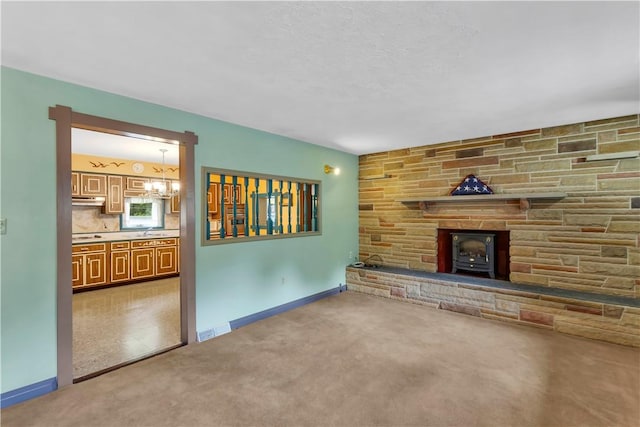 427 Harpers Ferry Rd, North Sewickley Twp, PA 15010 - unfurnished living room with carpet flooring, a wood stove, a sink, a chandelier, and baseboards