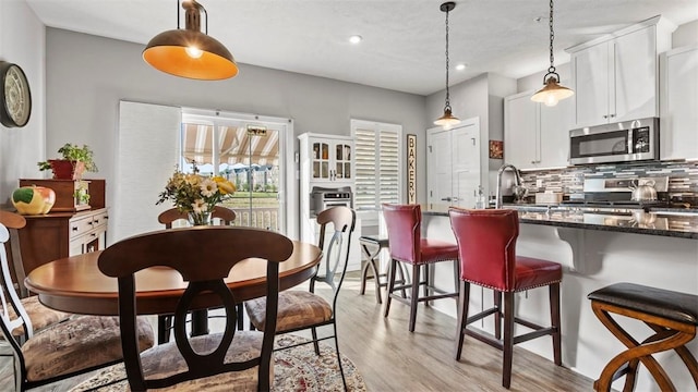 155 Bucktail Dr, Cranberry Twp, PA 16066 - kitchen with appliances with stainless steel finishes, decorative backsplash, a breakfast bar area, light wood finished floors, and decorative light fixtures