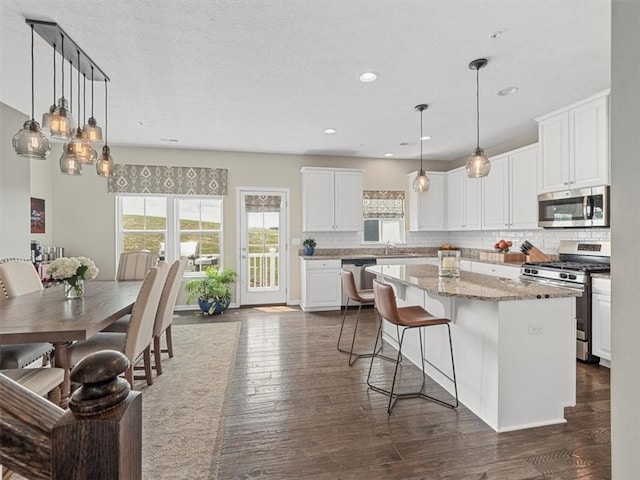 4046 Overview Dr, Cecil, PA 15317 - kitchen with stainless steel appliances, a kitchen island, a sink, decorative backsplash, and white cabinetry