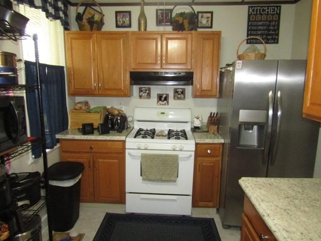 2445 Brownsville Rd, Carrick, PA 15210 - kitchen featuring gas range gas stove, under cabinet range hood, stainless steel fridge, light countertops, and brown cabinetry
