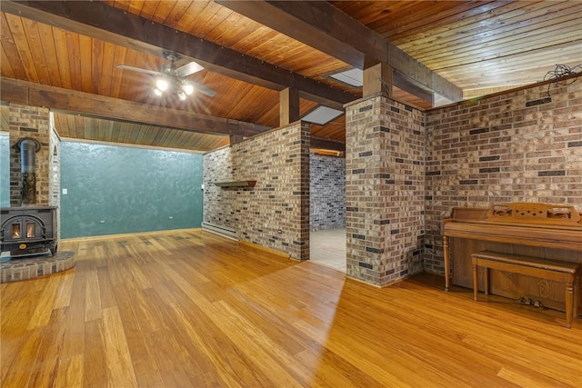 1369 Old Pulaski Rd, Neshannock Twp, PA 16105 - unfurnished living room featuring a wood stove, wood ceiling with exposed beams, hardwood / wood-style flooring, a ceiling fan, and brick wall