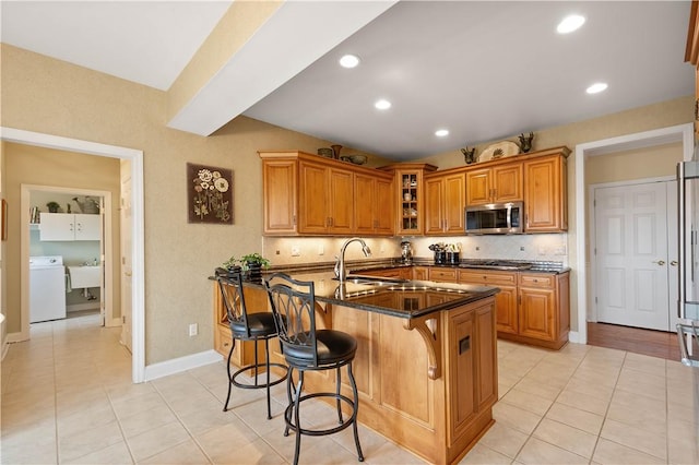 409 Foxwood Ln, Scott Twp Sal, PA 15220 - kitchen with appliances with stainless steel finishes, washer / clothes dryer, a sink, brown cabinets, and light tile patterned floors