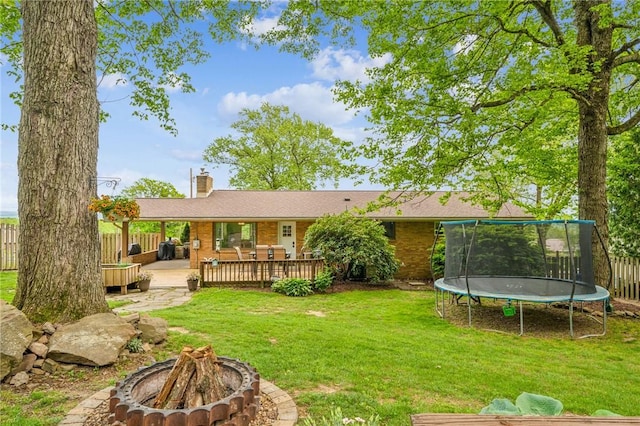 124 Hilton Rd, Unity Twp, PA 15601 - rear view of house featuring a fire pit, a trampoline, a chimney, a deck, and brick siding