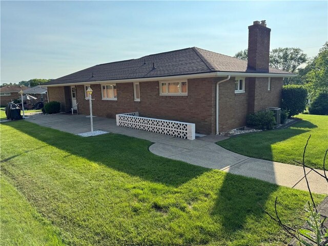 2122 Elizabeth Ct, Export, PA 15632 - back of property featuring a chimney, a patio area, a lawn, brick siding, and roof with shingles