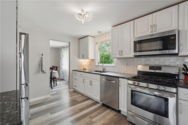105 Canaveral Dr, Penn Hills, PA 15235 - kitchen with stainless steel appliances, a sink, light wood finished floors, decorative backsplash, and white cabinets