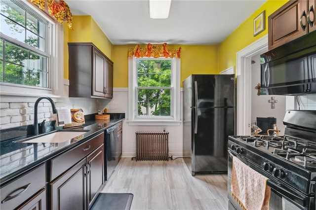 8243 High St, Mccandless, PA 15237 - kitchen with black appliances, radiator heating unit, a sink, light wood-type flooring, and tasteful backsplash