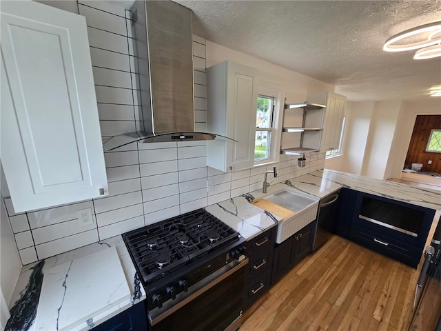 1102 Vermont Ave, White Oak, PA 15131 - kitchen featuring wall chimney range hood, a textured ceiling, gas stove, light stone countertops, and backsplash