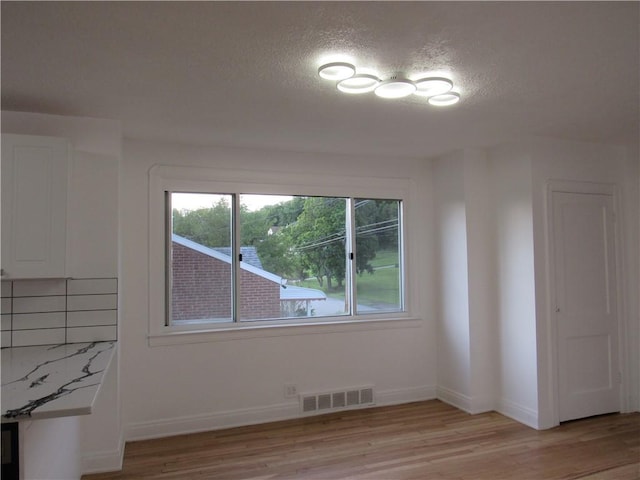 1102 Vermont Ave, White Oak, PA 15131 - unfurnished dining area with light wood-style flooring, a textured ceiling, and baseboards