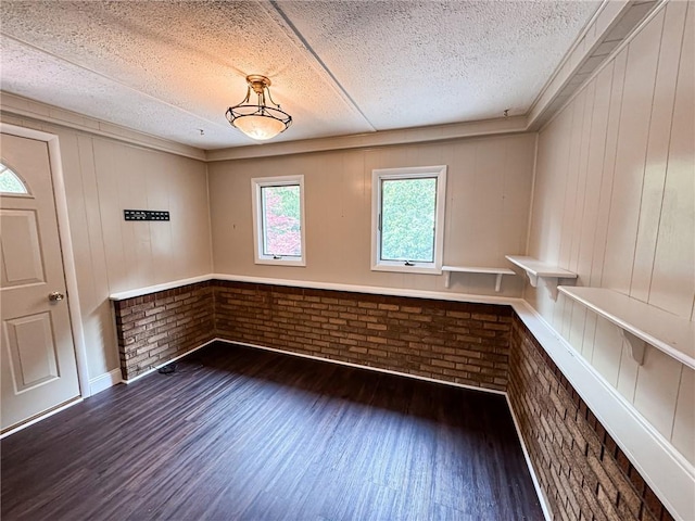 117 Harphen St, Versailles Boro, PA 15132 - unfurnished dining area with a textured ceiling, wood finished floors, brick wall, and wooden walls