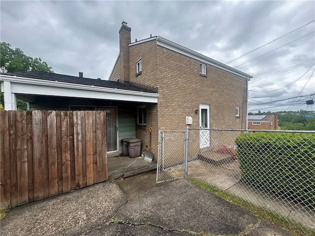 2317 Parklyn St, Overbrook, PA 15234 - rear view of house with brick siding, a gate, and a chimney