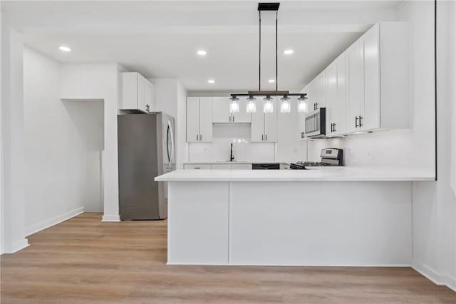 220 Dewey St, Edgewood, PA 15218 - kitchen with stainless steel appliances, a peninsula, light countertops, light wood-style floors, and recessed lighting