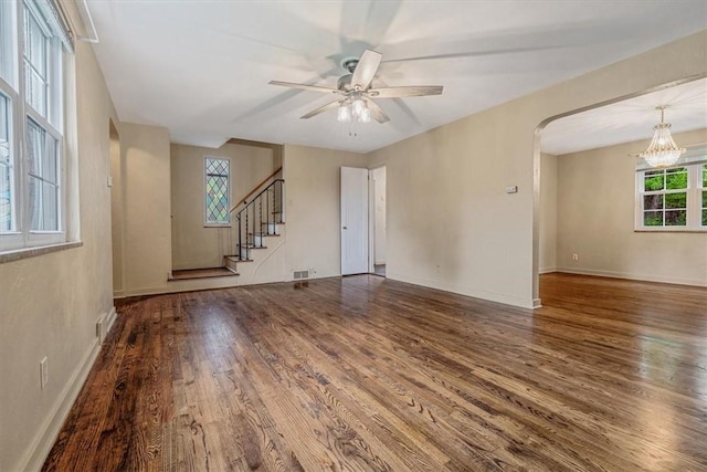 142 Slater Dr, Pleasant Hills, PA 15236 - empty room featuring wood finished floors, arched walkways, a ceiling fan, a chandelier, and stairway