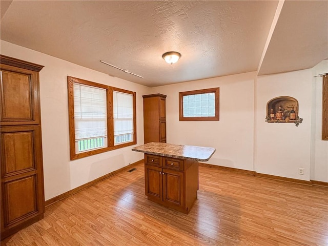 2701 Lafayette St, Mckeesport, PA 15132 - kitchen with light wood-type flooring, brown cabinets, a textured ceiling, baseboards, and a center island
