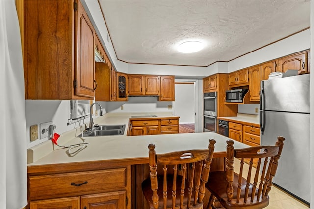 48 Green Crescent Dr, South Strabane, PA 15301 - kitchen featuring appliances with stainless steel finishes, a sink, brown cabinetry, a textured ceiling, and a peninsula
