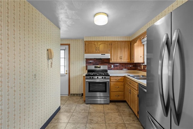 719 12th St, Pitcairn, PA 15140 - kitchen featuring stainless steel appliances, under cabinet range hood, light countertops, wallpapered walls, and a sink