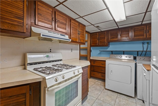 719 12th St, Pitcairn, PA 15140 - kitchen featuring white gas stove, under cabinet range hood, independent washer and dryer, light countertops, and a paneled ceiling