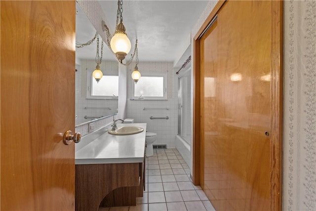 719 12th St, Pitcairn, PA 15140 - full bath with toilet, tile patterned flooring, vanity, combined bath / shower with glass door, and tile walls