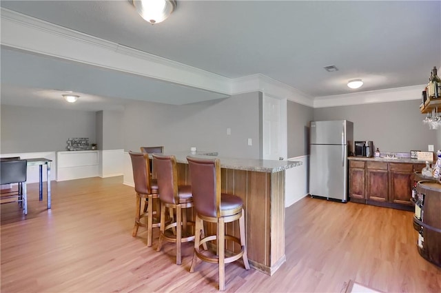 8014 Maureen Dr, Cranberry Twp, PA 16066 - kitchen featuring freestanding refrigerator, light wood finished floors, brown cabinets, a kitchen breakfast bar, and ornamental molding