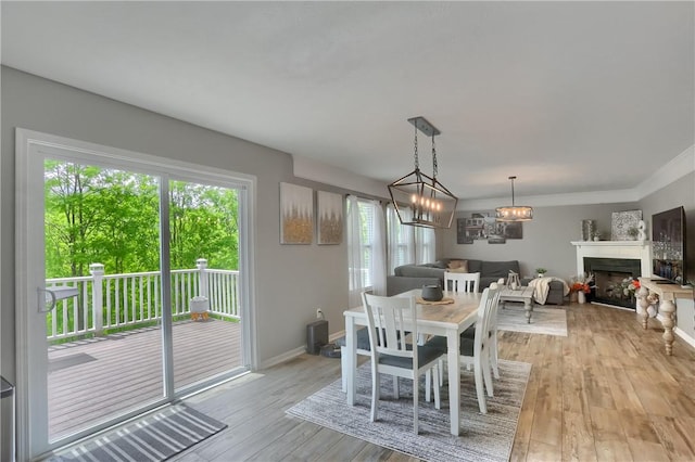 8014 Maureen Dr, Cranberry Twp, PA 16066 - dining room with light wood-style floors, a fireplace, a chandelier, ornamental molding, and baseboards