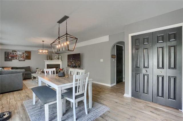 8014 Maureen Dr, Cranberry Twp, PA 16066 - dining area featuring arched walkways, a fireplace, light wood-type flooring, and baseboards